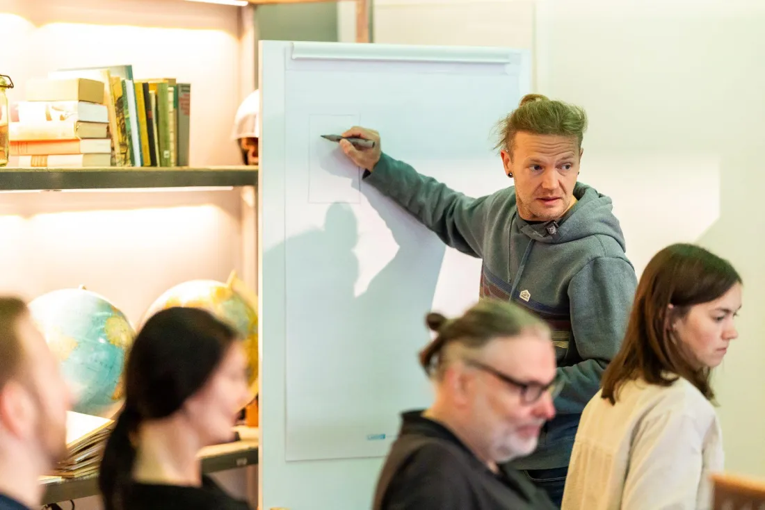 Robby Schadt erklärt am Flipchart im Seminarraum vor einer Teilnehmergruppe